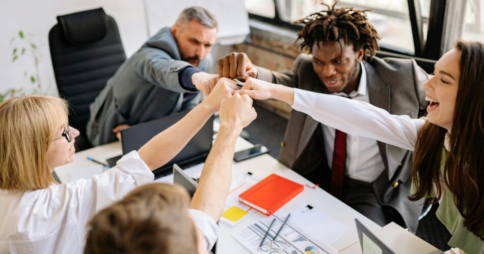 a group of people sitting at a table doing fist bump