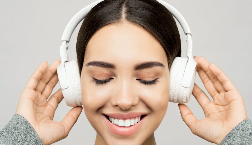 woman in gray sweater wearing white headphones
