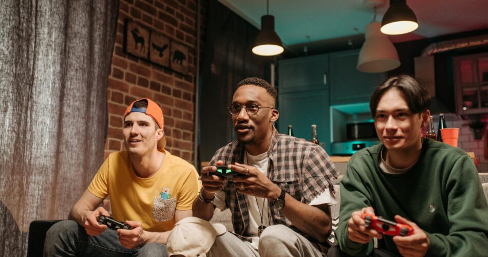 men sitting on sofa holding game controllers